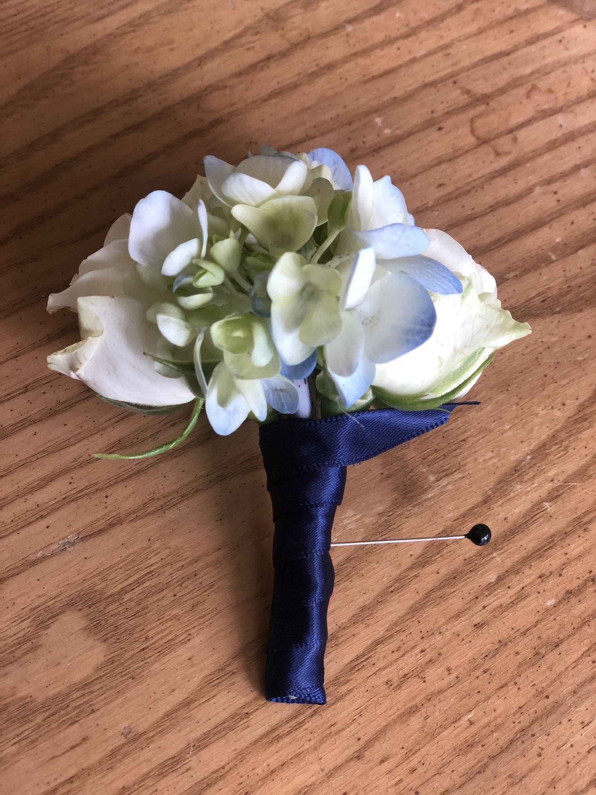 A bouquet of flowers is pinned to a wooden table.