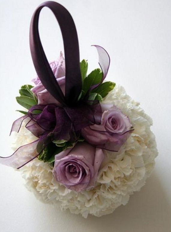 A white and purple flower arrangement with a purple ribbon