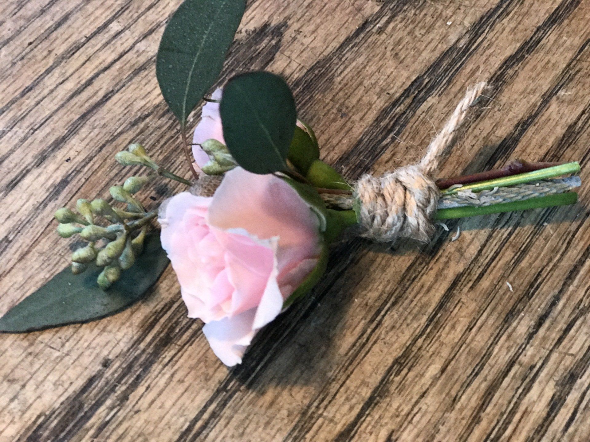 A close up of a pink rose on a wooden table.