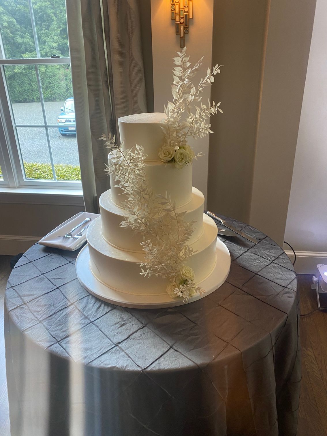 A white wedding cake is sitting on top of a round table.
