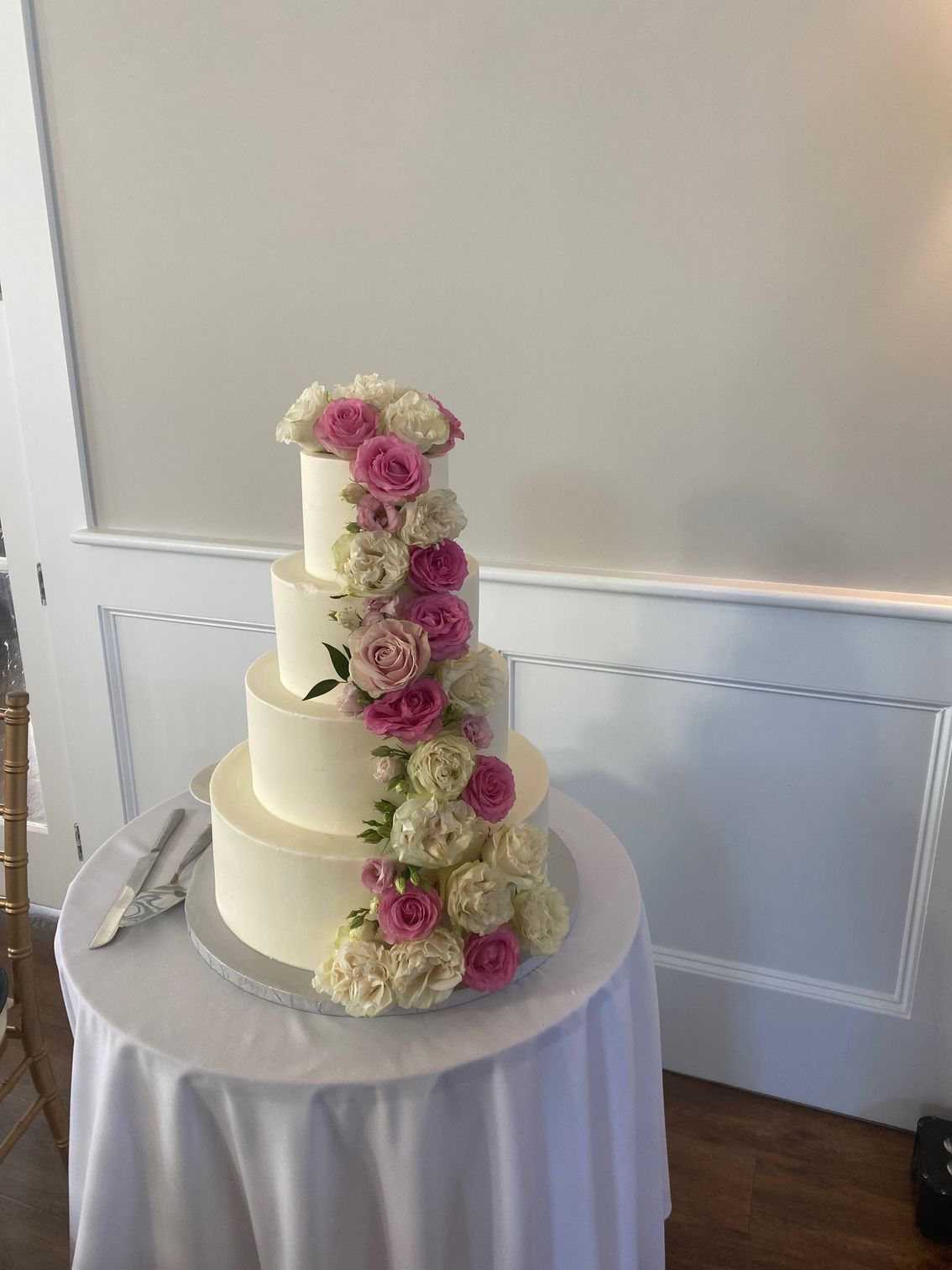 A wedding cake with pink and white flowers is sitting on a table.