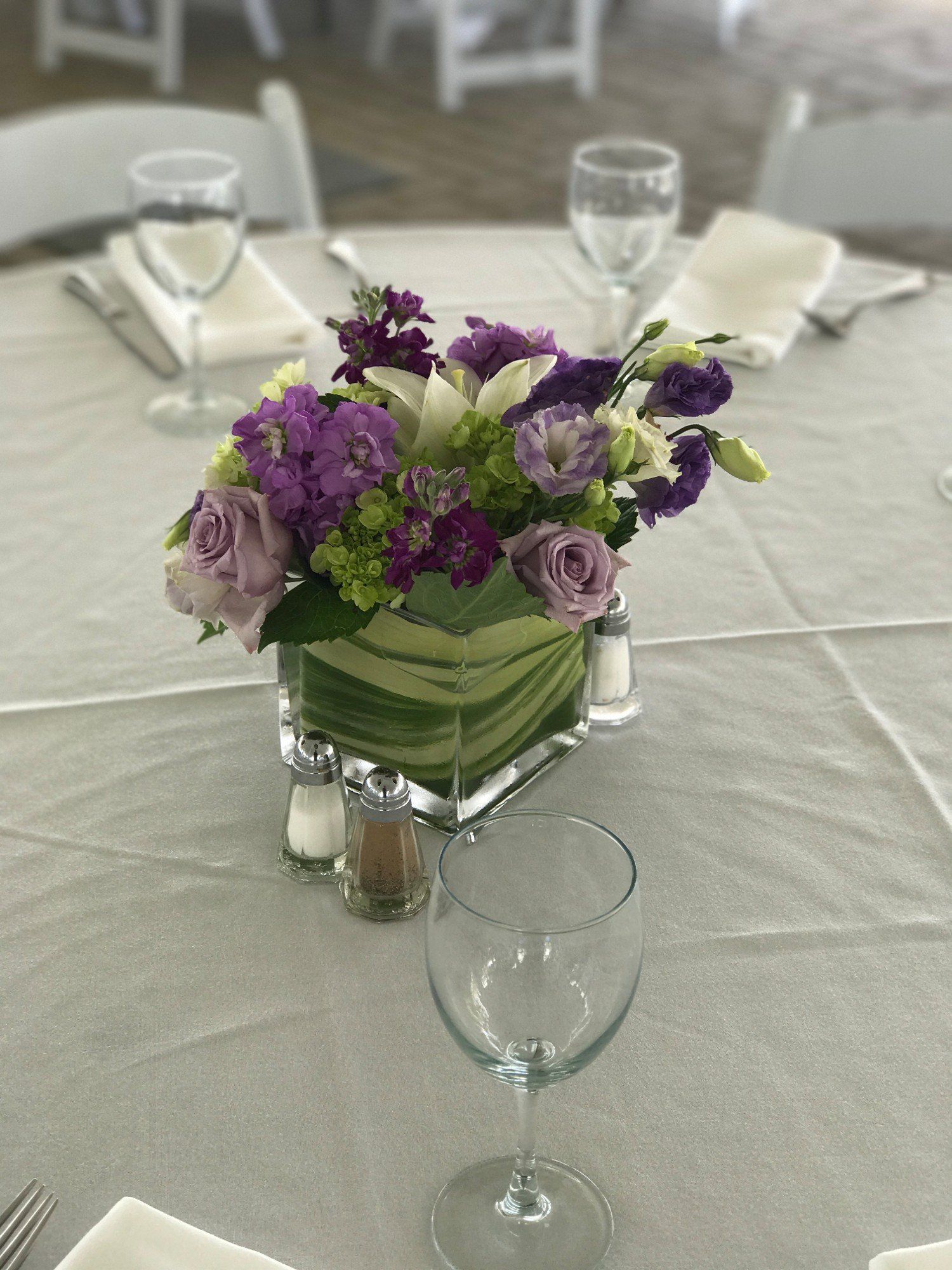 A table with a vase of purple flowers and a wine glass on it.