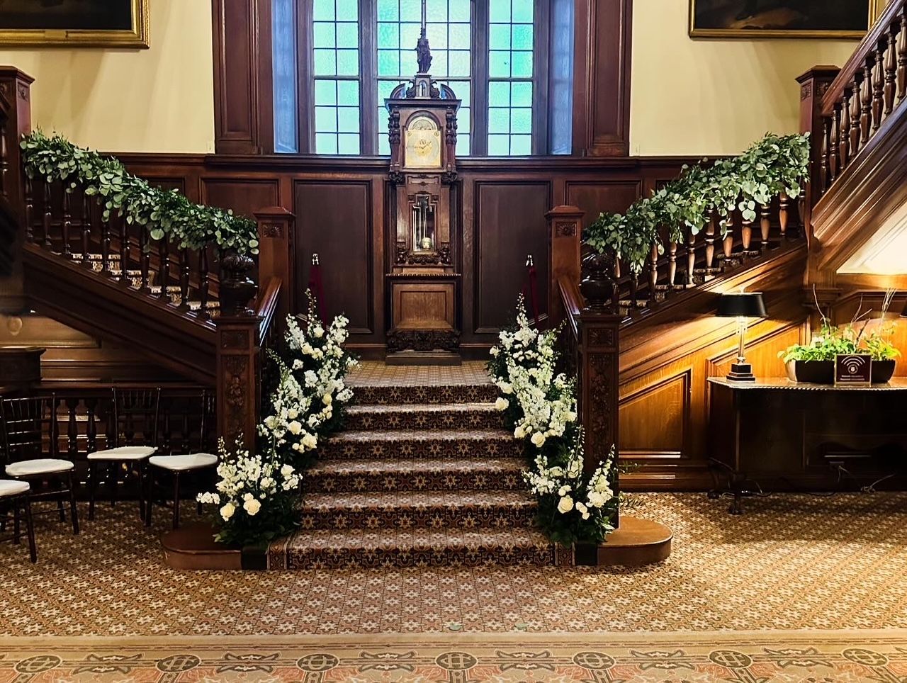 The stairs are decorated with white flowers and greenery