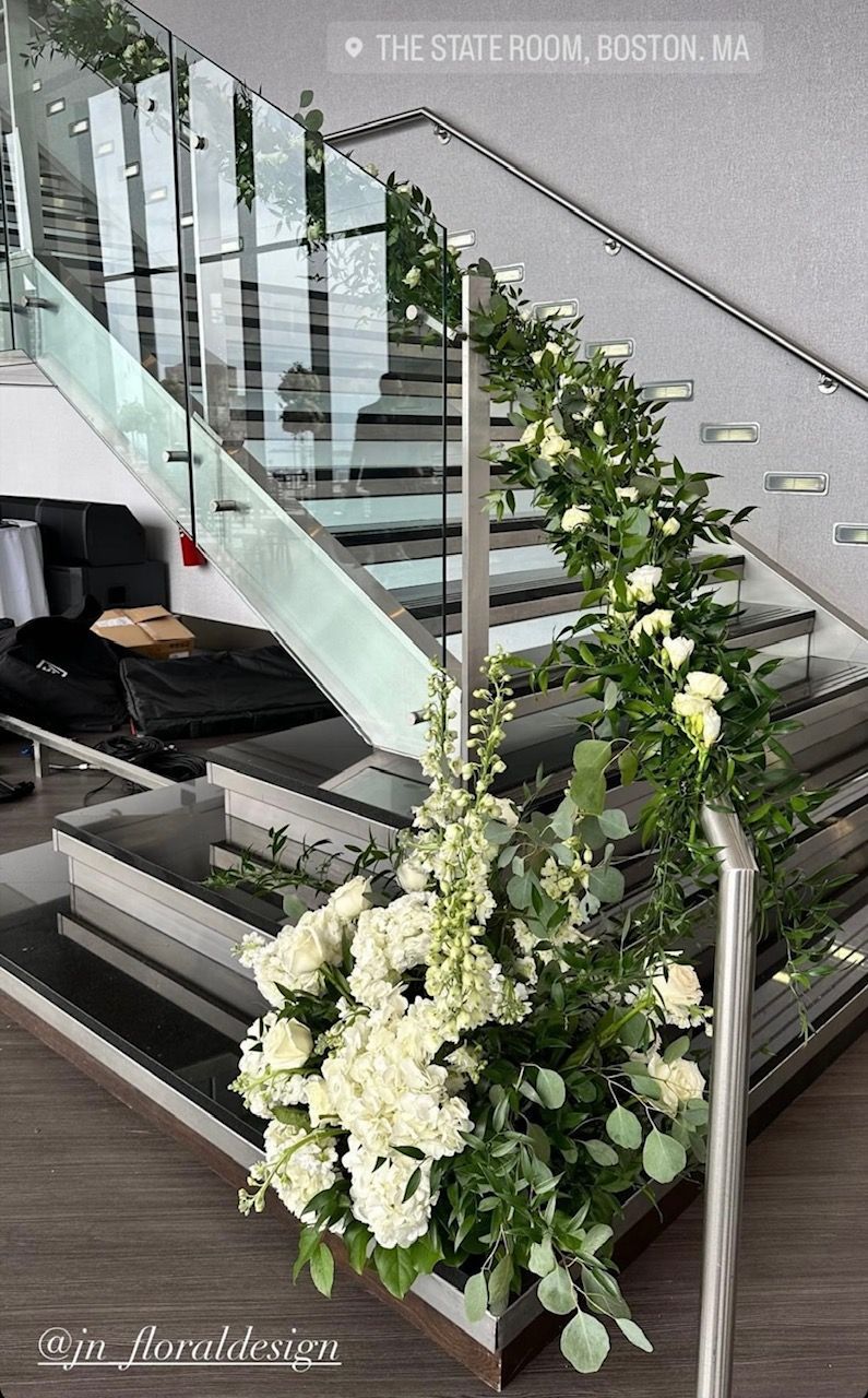 A staircase decorated with white flowers and greenery.