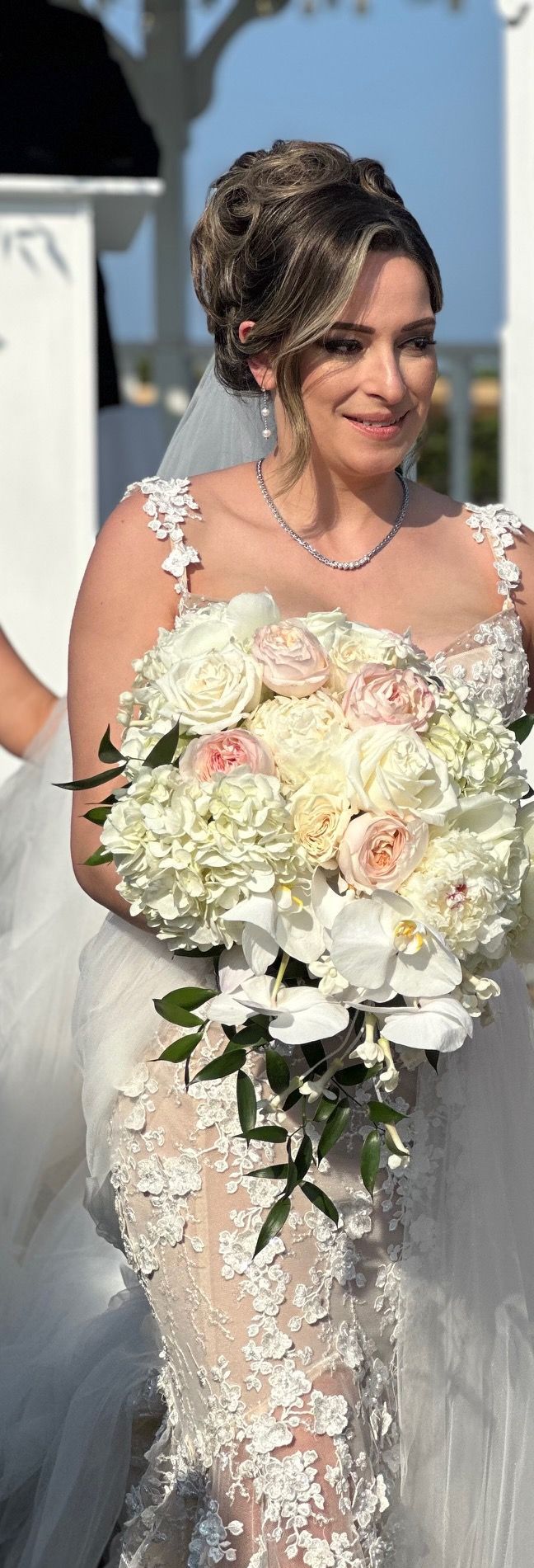 A bride in a wedding dress is holding a bouquet of white flowers.