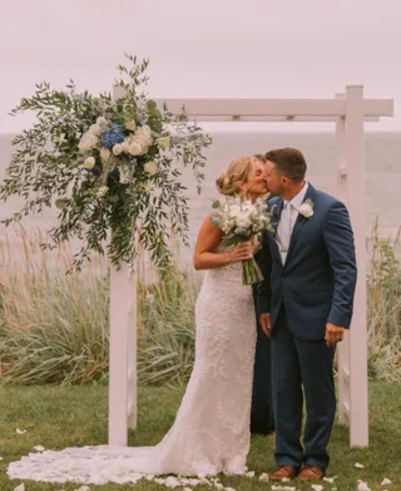 A bride and groom kissing in front of a wedding arch