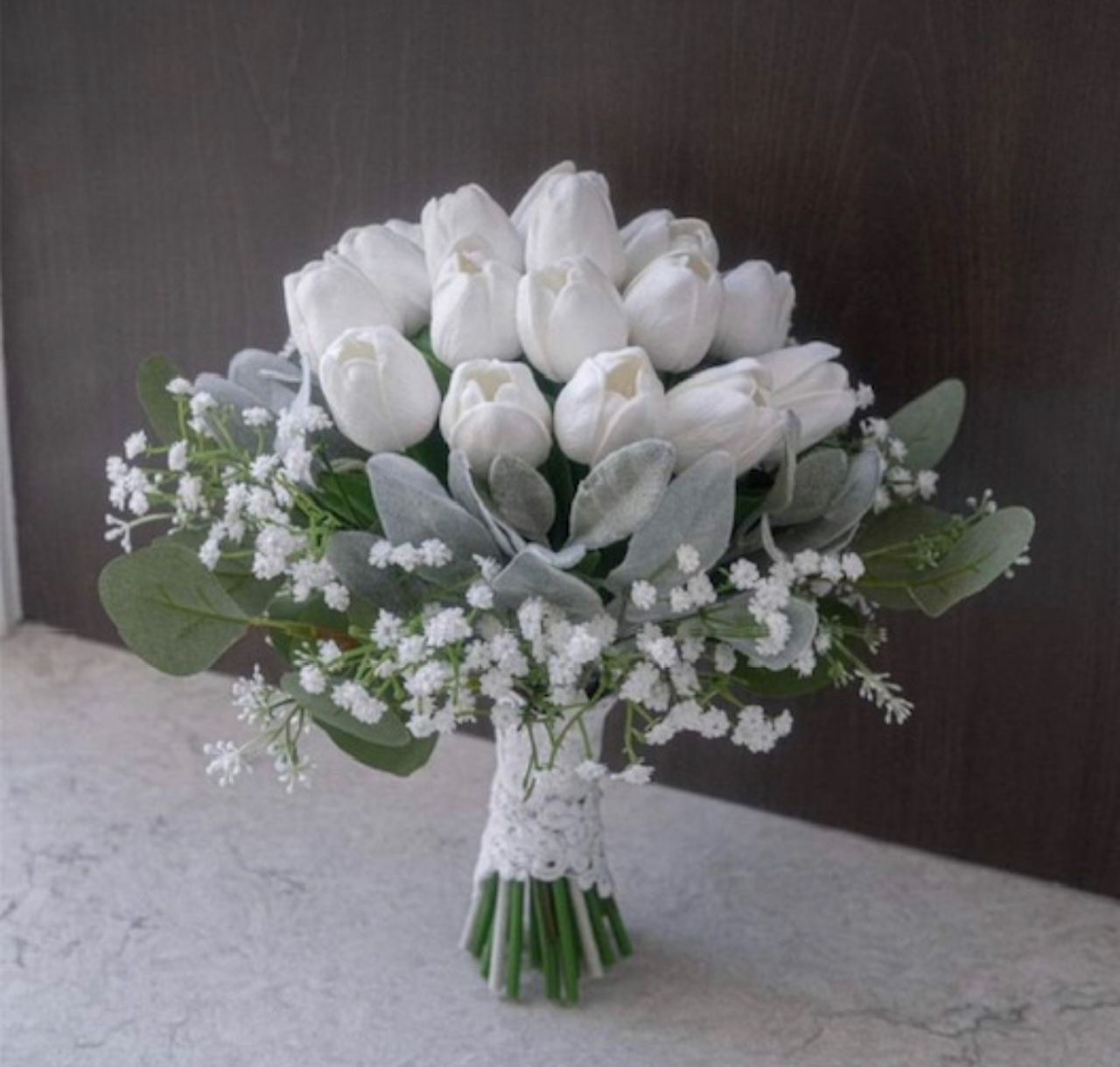 A bouquet of white tulips and baby 's breath on a table