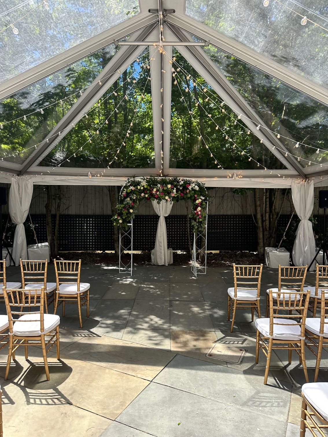 A wedding ceremony is taking place under a clear tent.