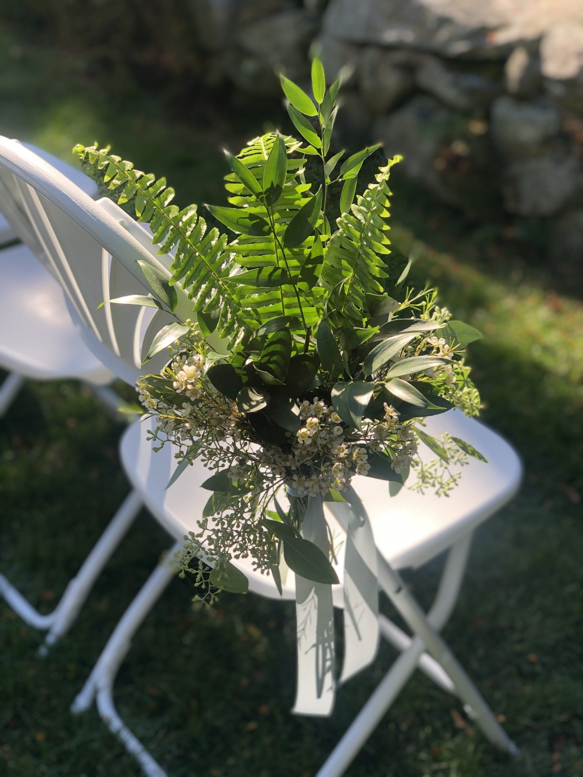 A white folding chair with a bouquet of flowers on it.