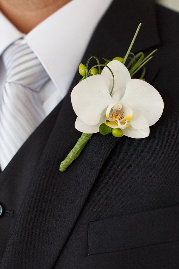 A man in a suit has a white flower pinned to his jacket