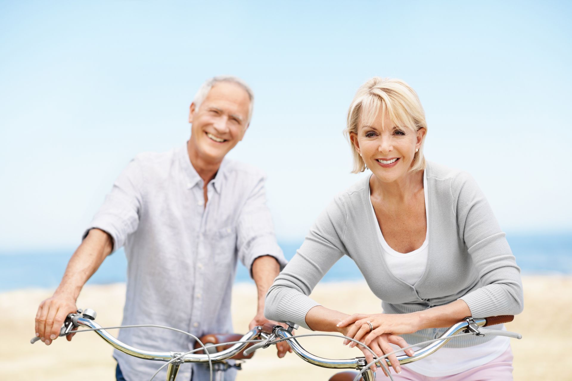 A man and a woman are hugging and eating ice cream by the water.