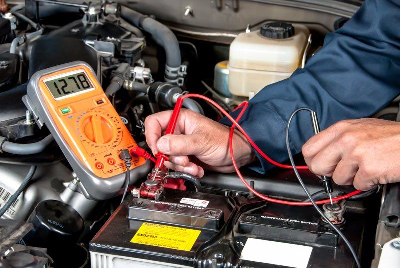 mechanic testing voltage on a car battery