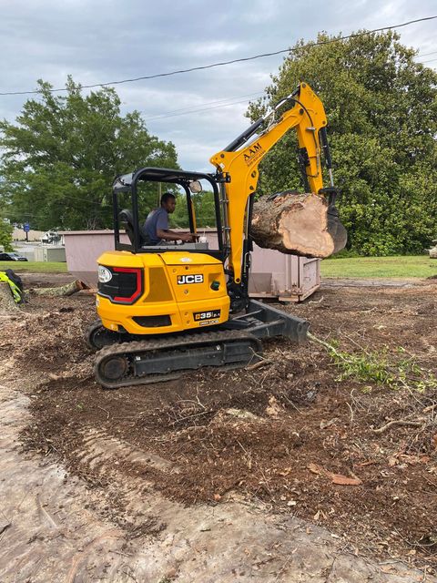 A man is driving a small yellow excavator in a dirt field.