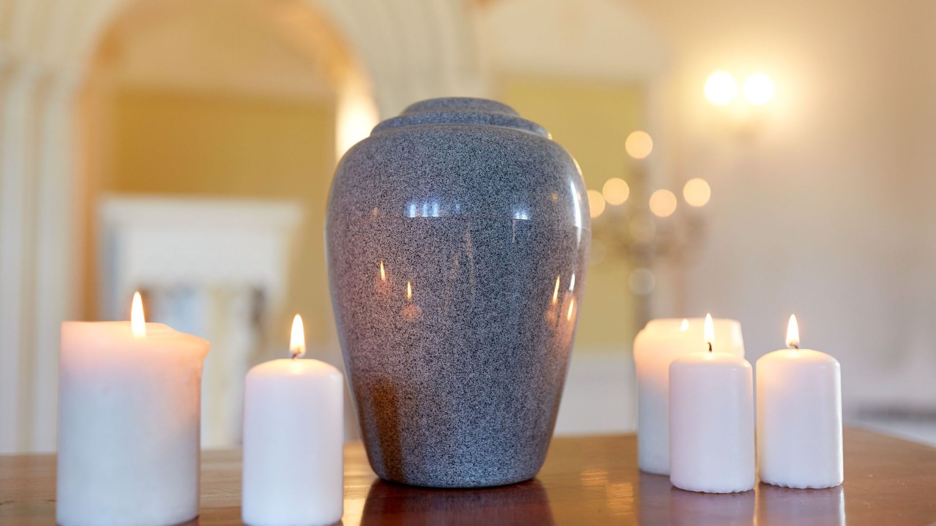 Cremation Urn on a table with lit candles around it