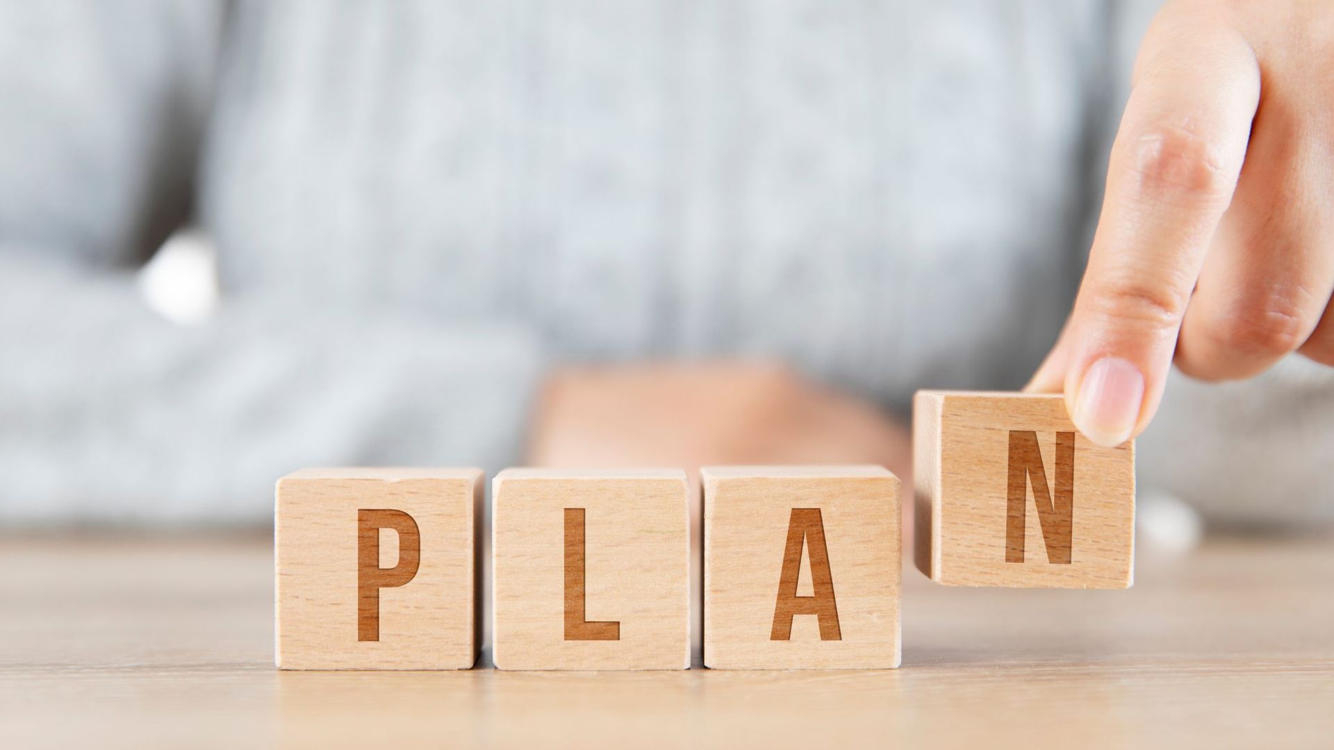 a person spelling the word plan with wooden blocks