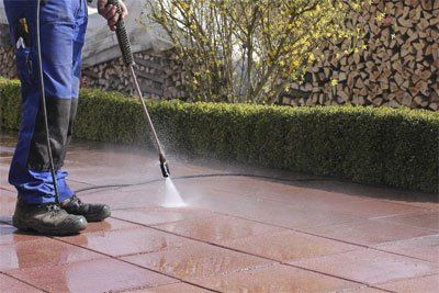 person jet washing a paved area