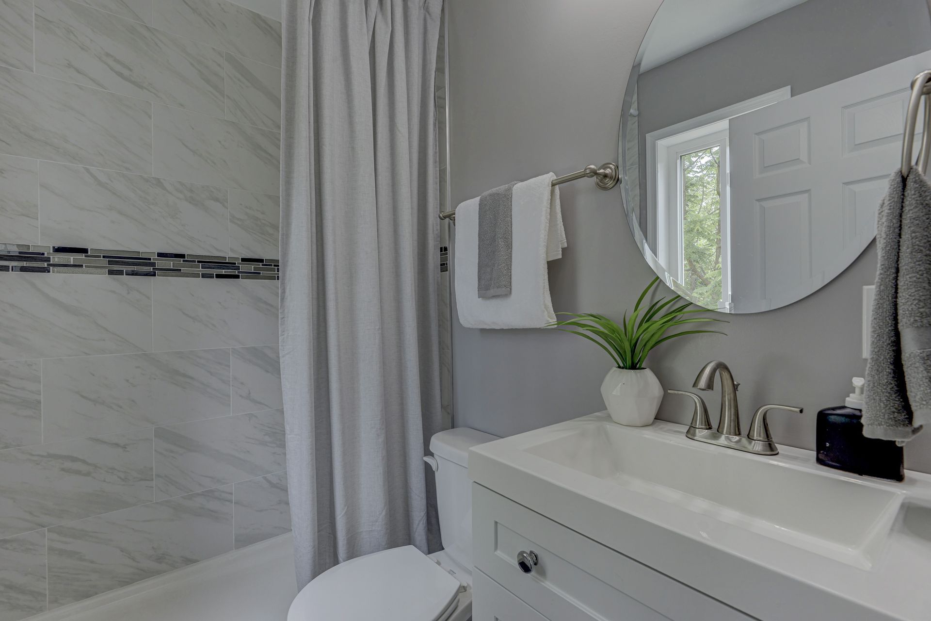 A bathroom with a sink , toilet , shower and mirror.