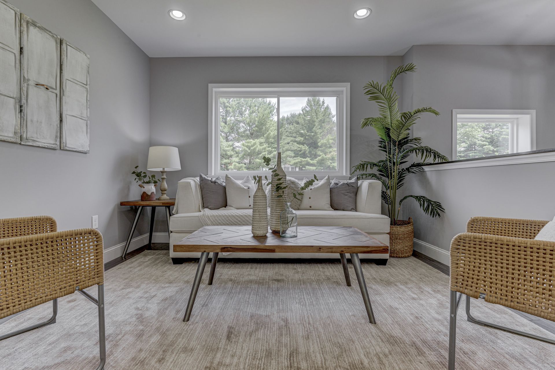 A living room with a couch , chairs , a coffee table and a window.
