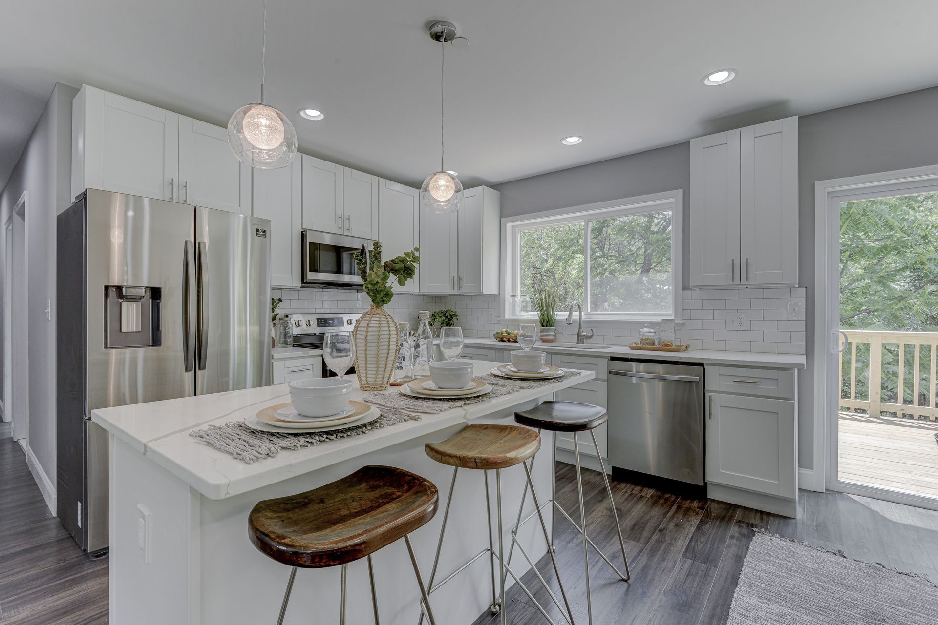 A kitchen with white cabinets , stainless steel appliances , and a large island.