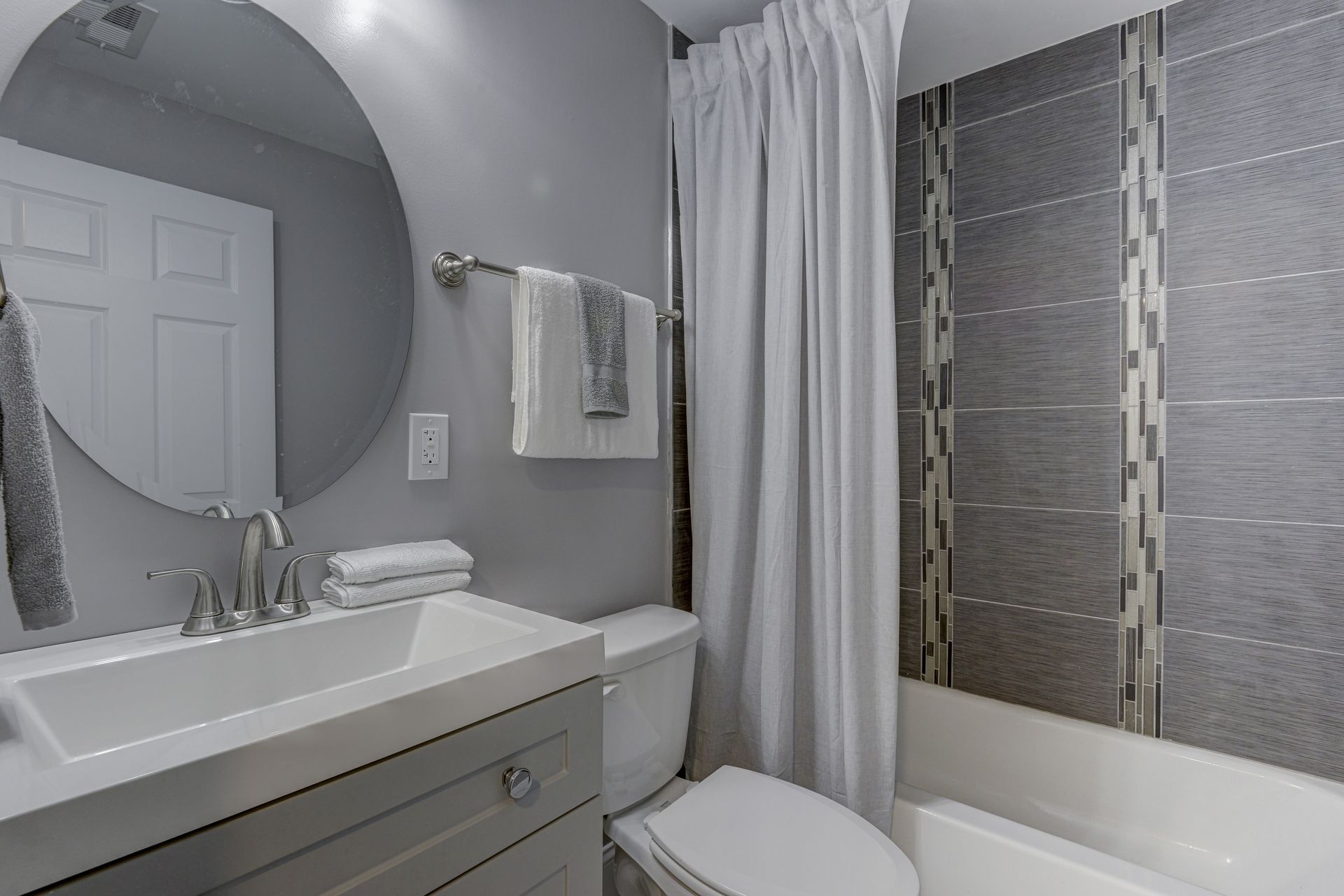 A bathroom with a sink , toilet , bathtub and mirror.