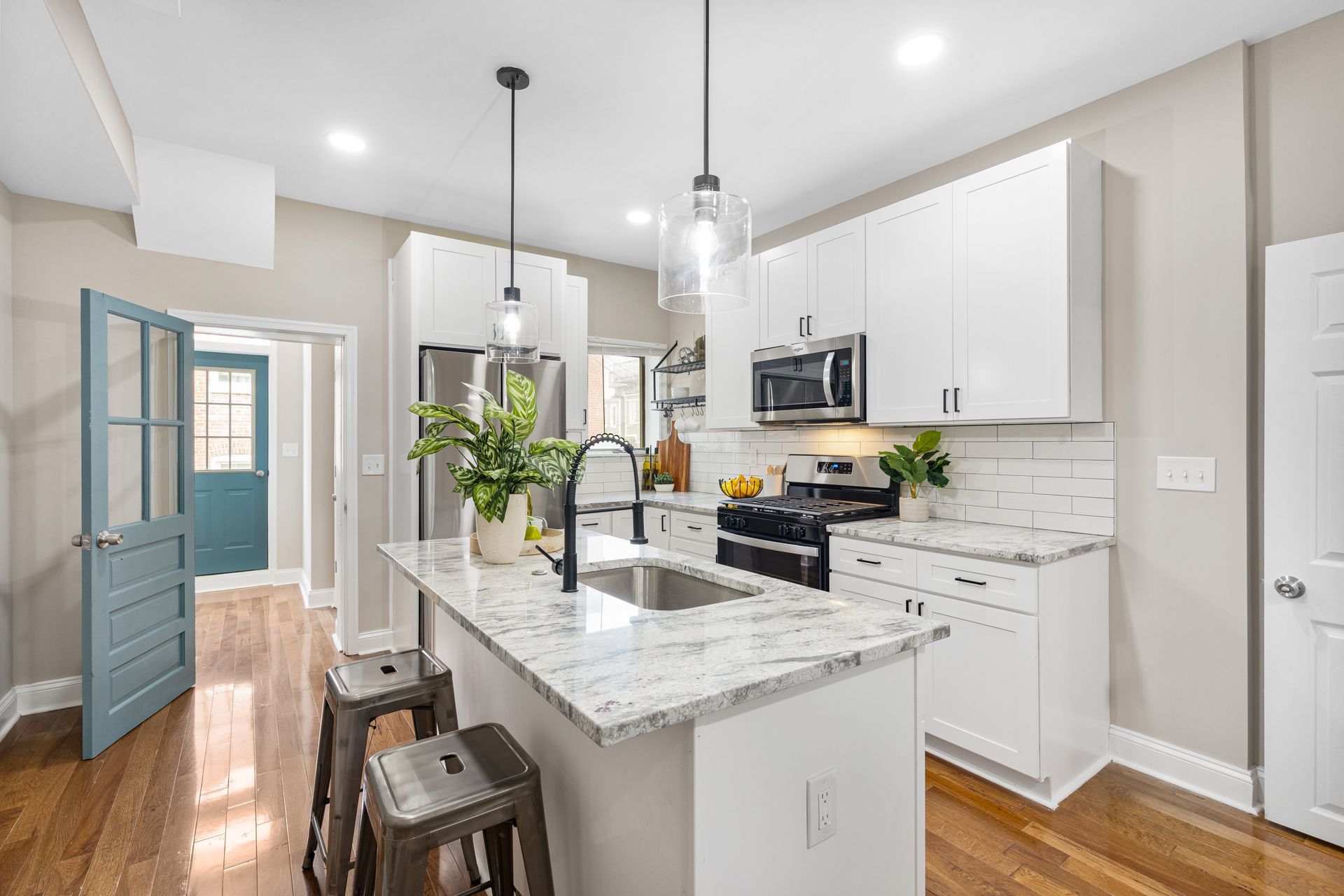A kitchen with white cabinets , granite counter tops , stainless steel appliances and a large island.
