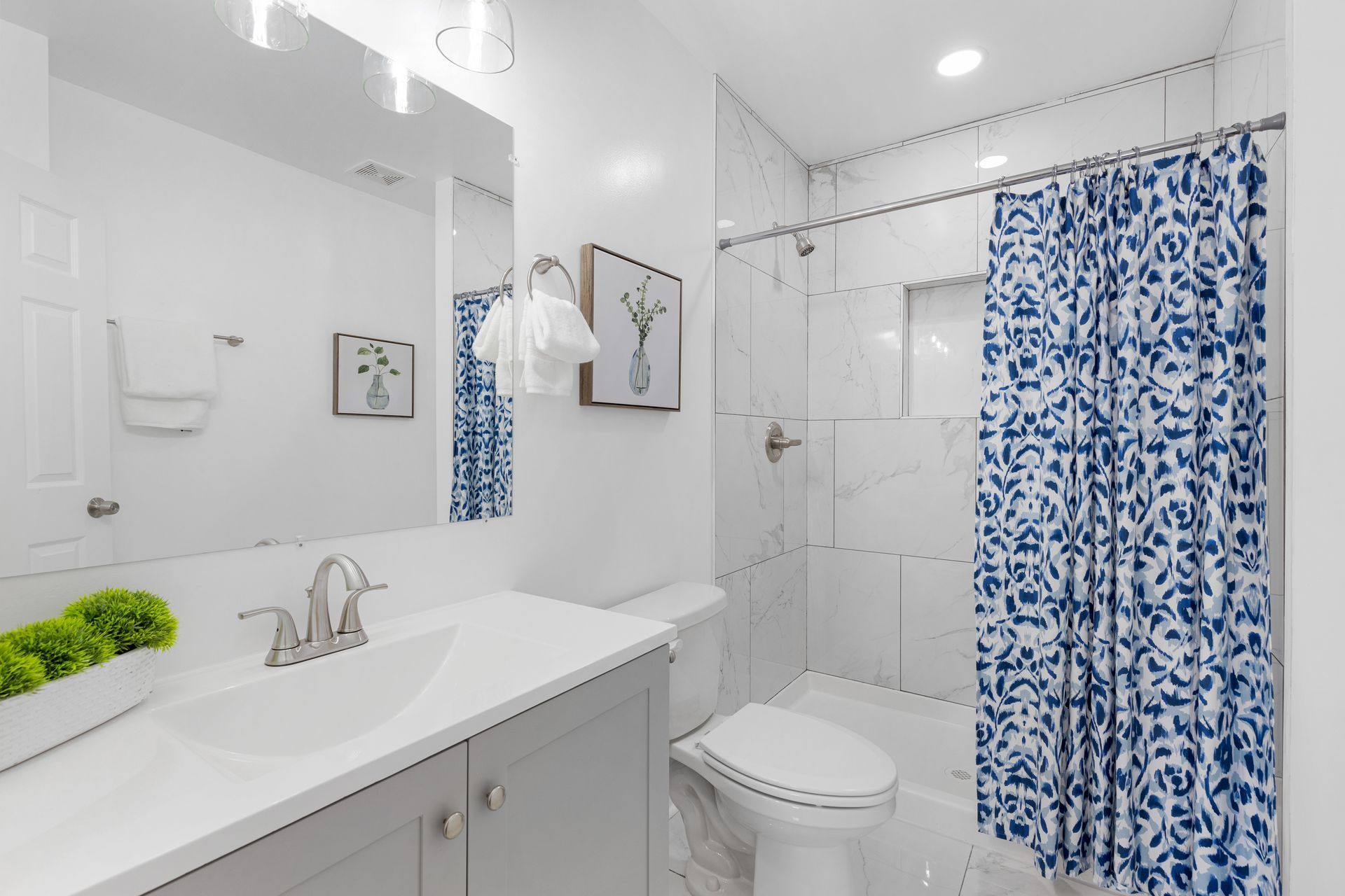 A bathroom with a toilet , sink , shower and blue shower curtain.