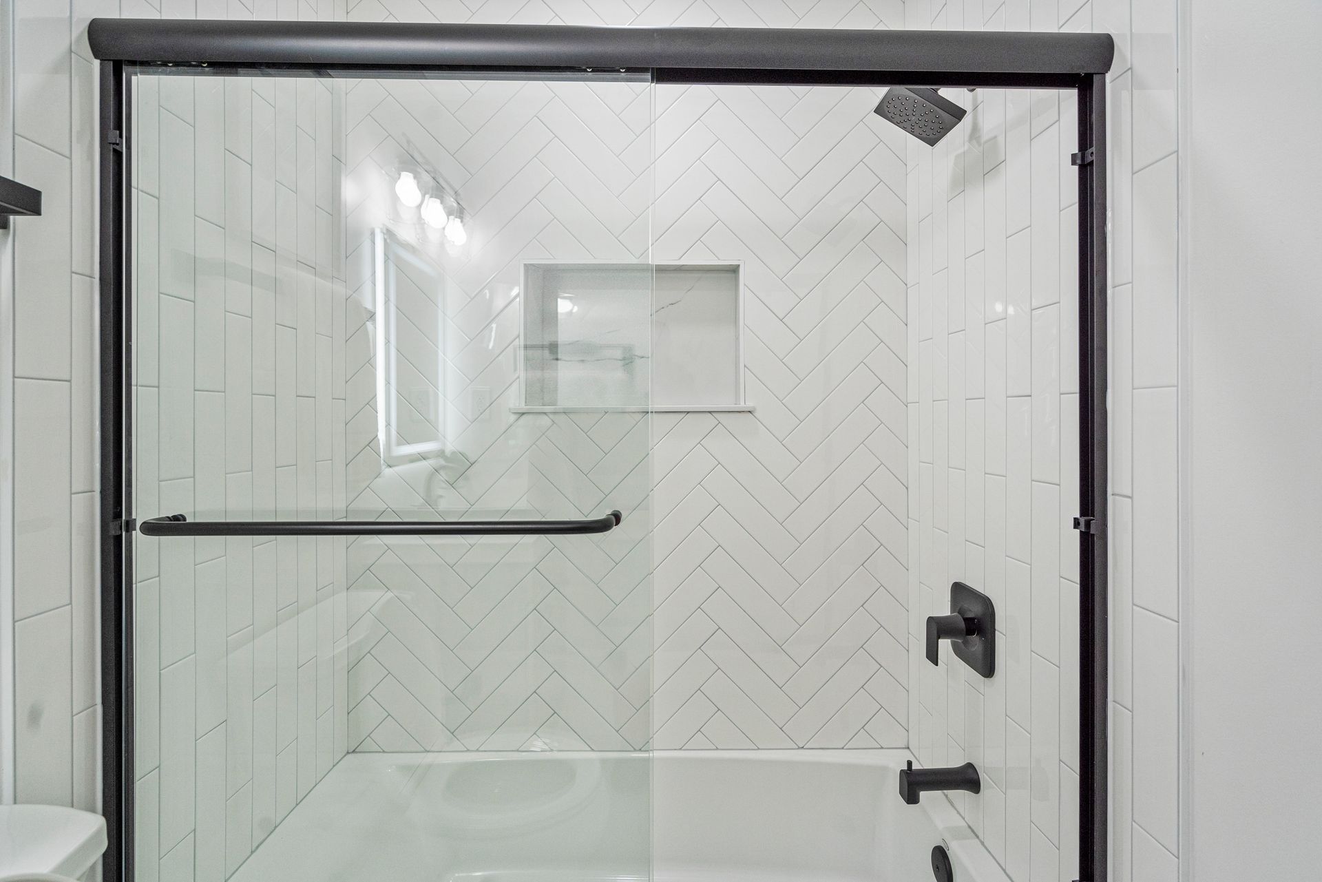 A bathroom with a sliding glass shower door and a bathtub.