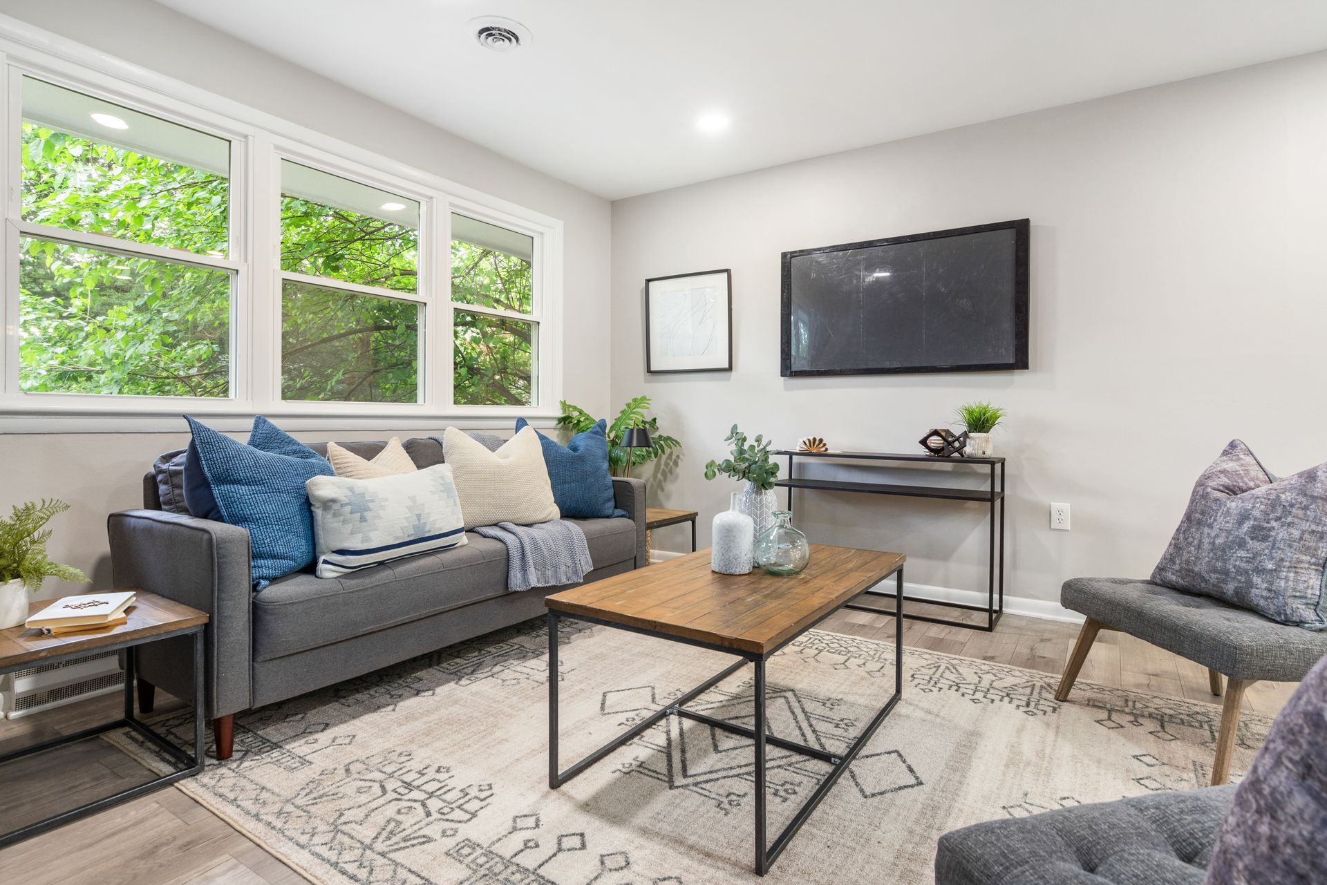A living room with a couch , chair , coffee table and television.