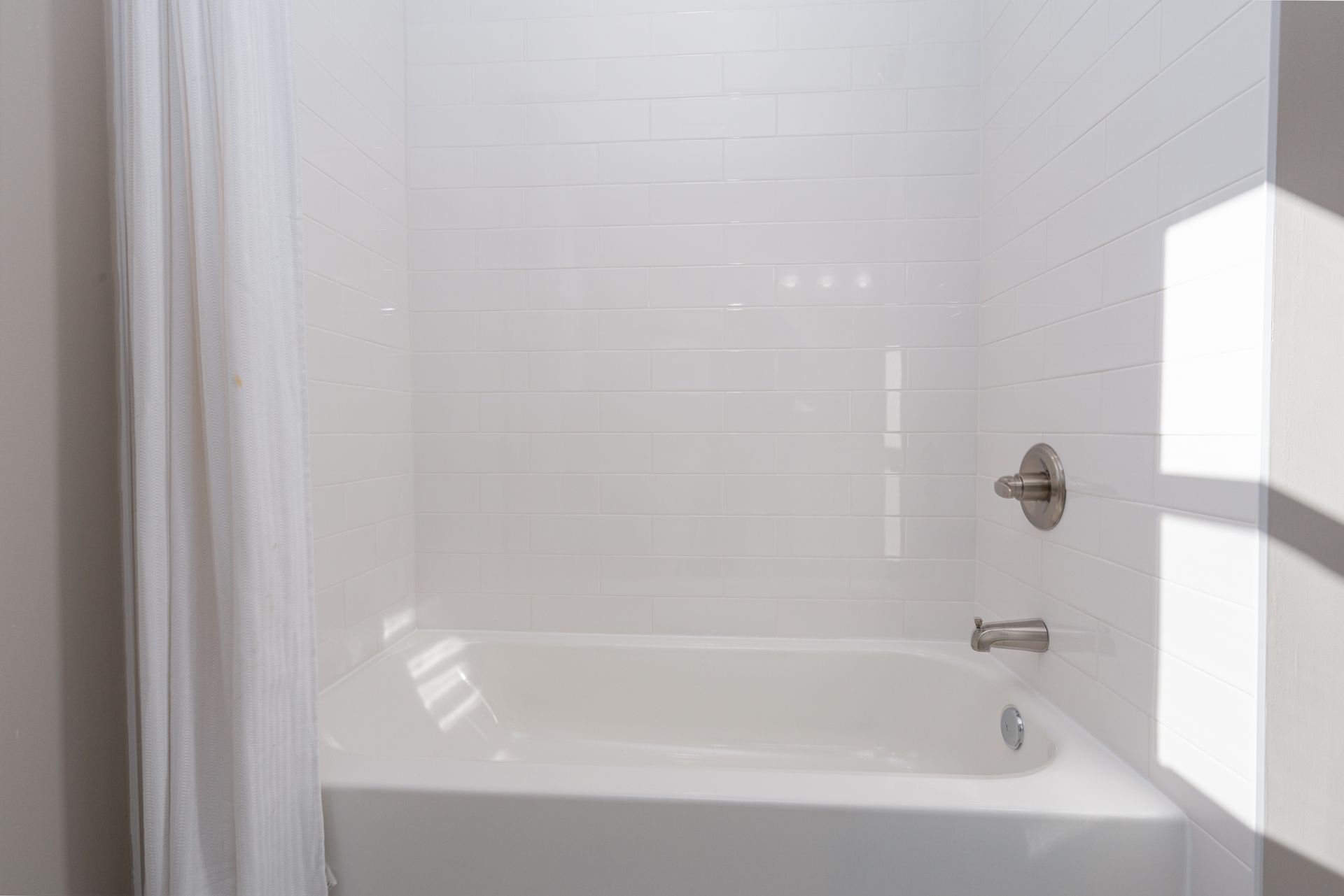 A bathroom with a bathtub and shower curtain.