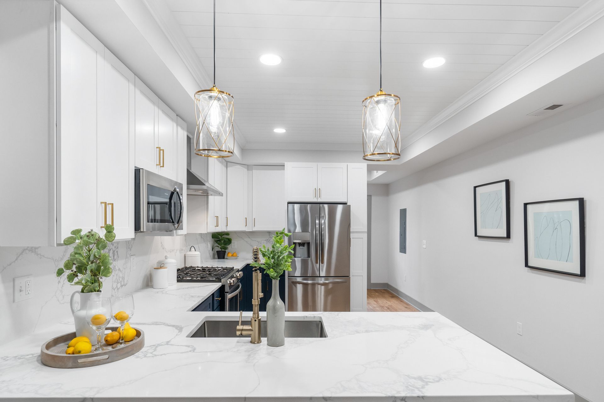 A kitchen with white cabinets , stainless steel appliances , a sink , and a refrigerator.