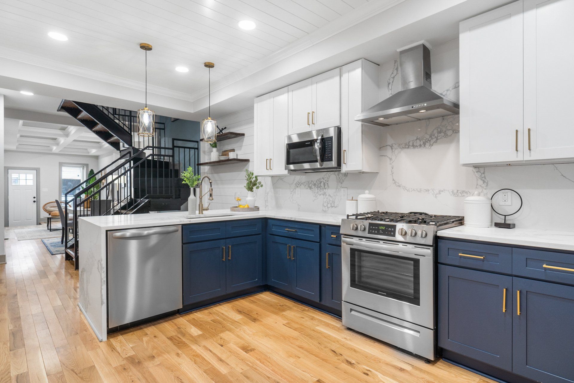 A kitchen with blue cabinets , white cabinets , stainless steel appliances and hardwood floors.