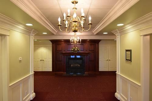 A hallway with a fireplace and a chandelier hanging from the ceiling