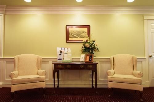 A room with two chairs and a table with a picture on the wall