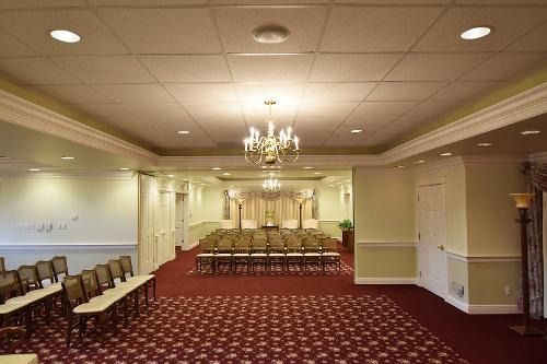 A large room with rows of chairs and a chandelier.