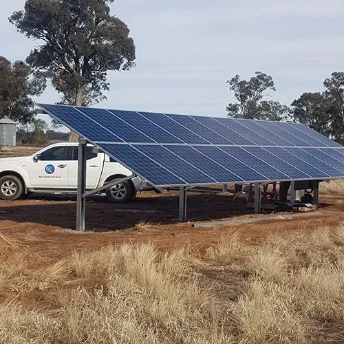 A truck is parked next to a solar panel in a field