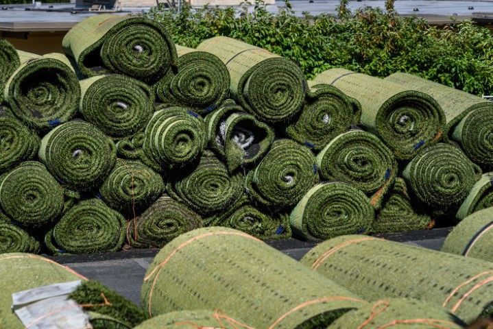 Rolls of green artificial turf stacked outdoors.