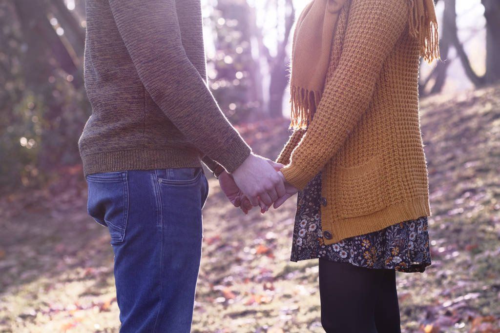 Hände halten, gelber Pullover, Kleid, geblümtes Kleid, bunte Blätter, warme herbstliche Tagen.