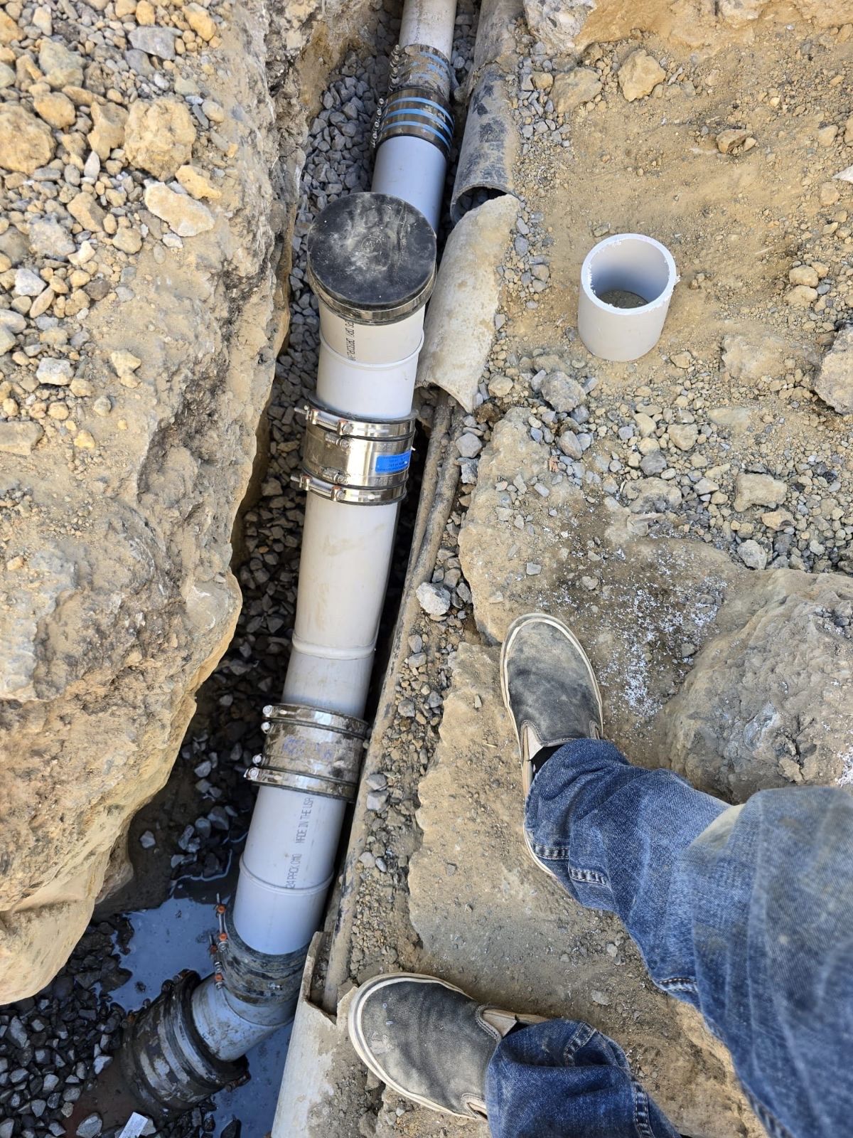 A man is holding a flashlight and looking into a hole in the floor.