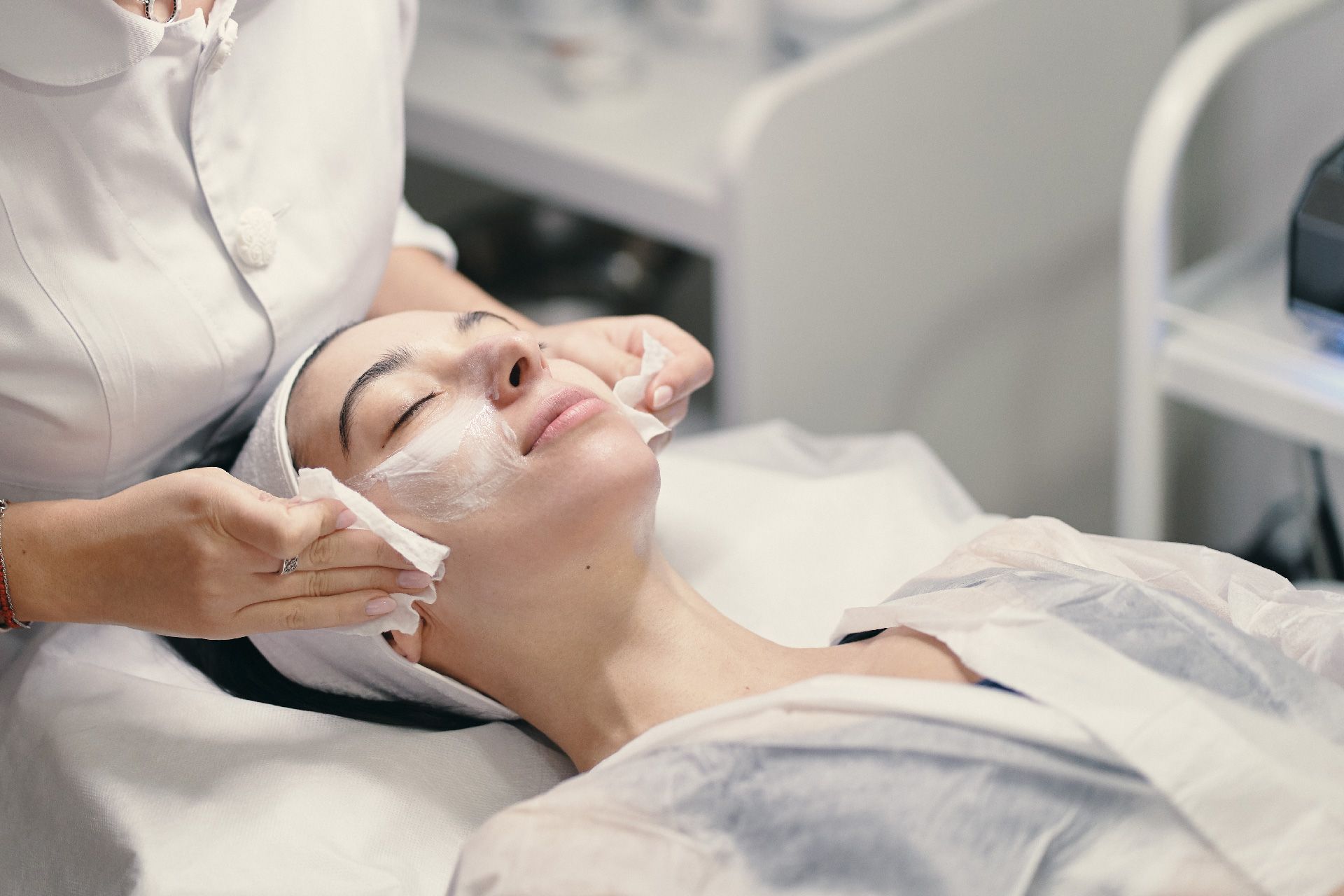 Mujer recibiendo un tratamiento facial en un spa. La terapeuta le aplica el producto en el rostro con discos de algodón.