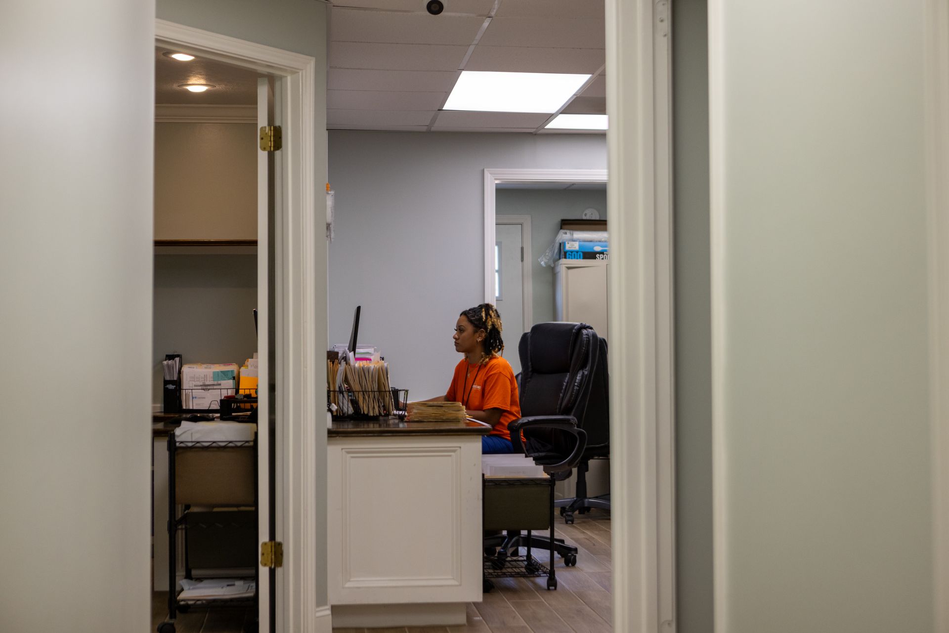 A woman is sitting at a desk in an office with a laptop.