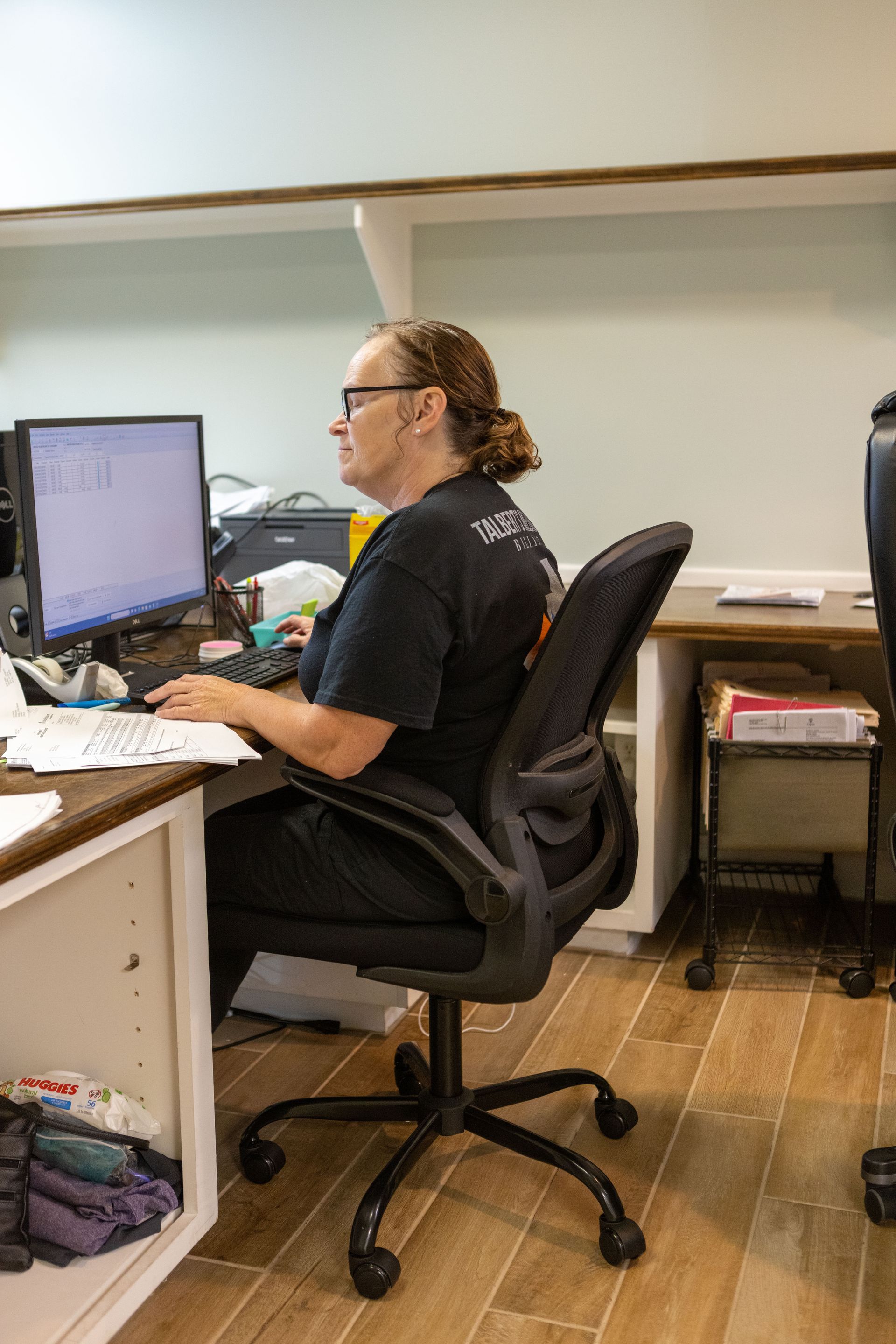 A woman is sitting at a desk in front of a computer.
