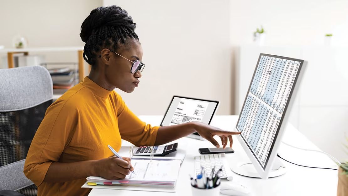 A woman is sitting at a desk using a computer.