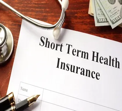 A short term health insurance form with a pen and stethoscope