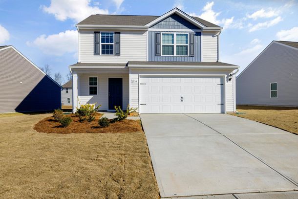 A white house with a garage and a driveway in a residential area.