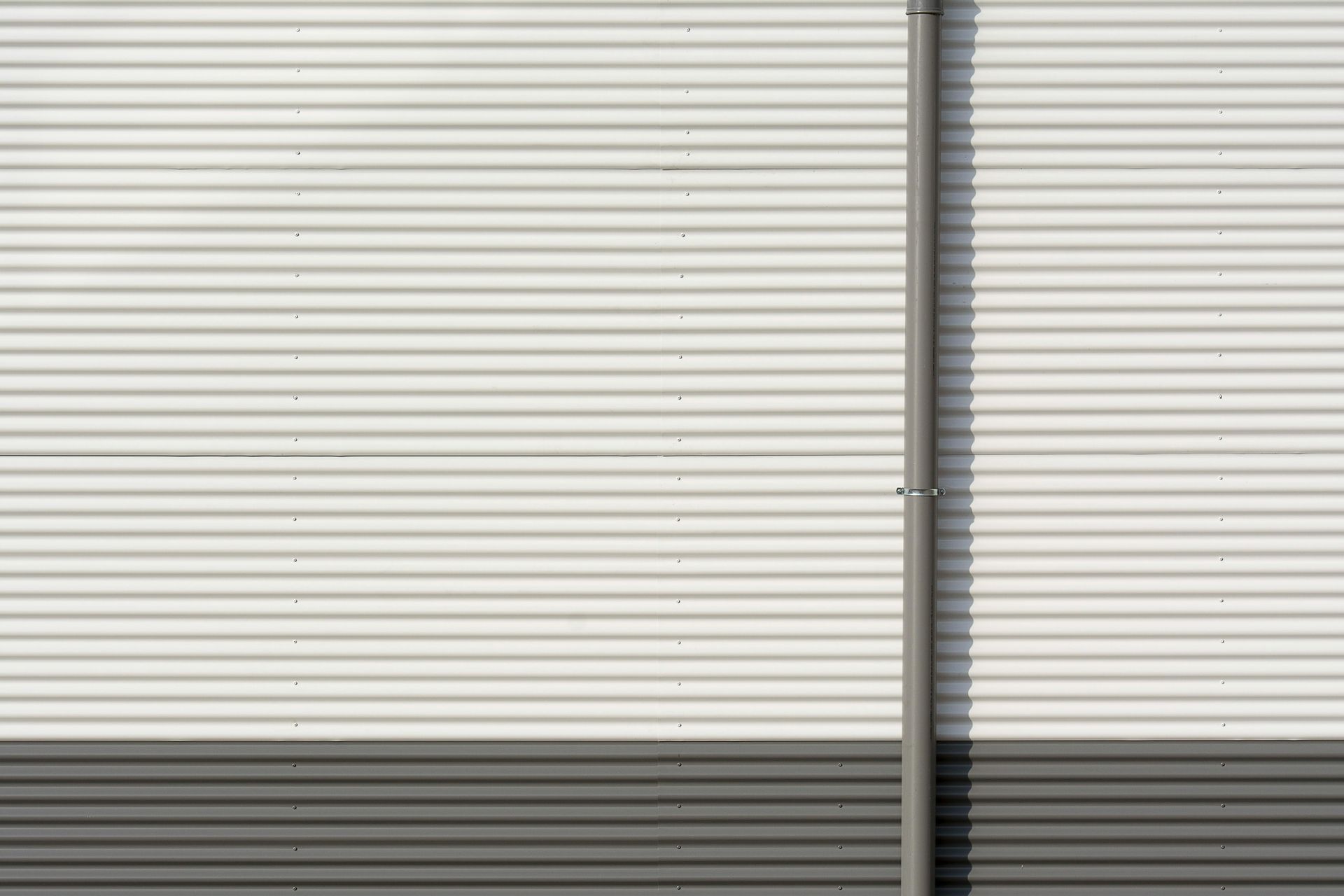 A close up of a white wall with a drainpipe on it.