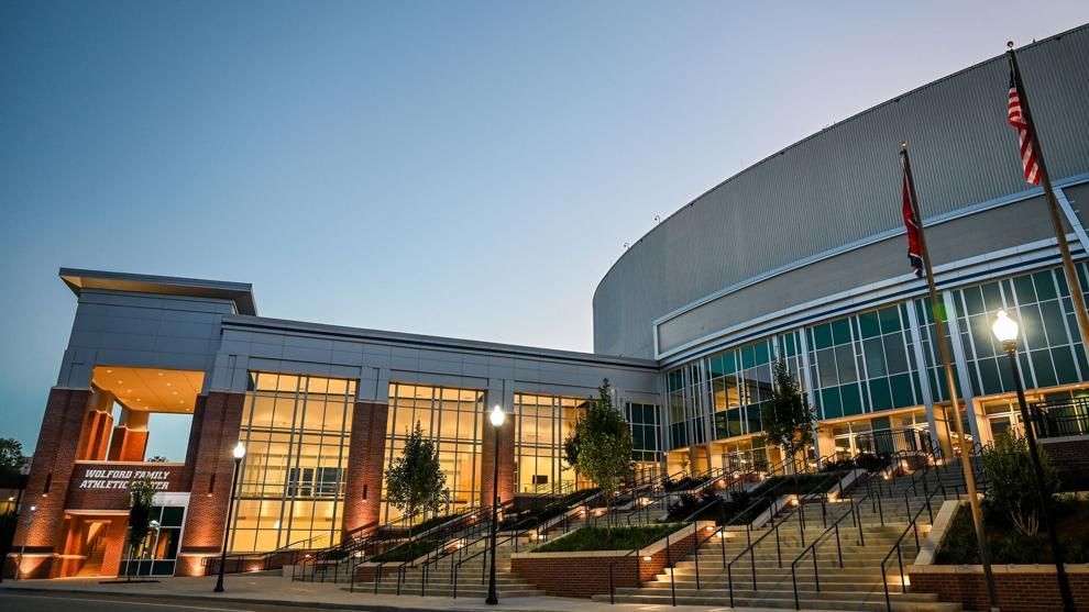 A large building with stairs leading up to it is lit up at night.
