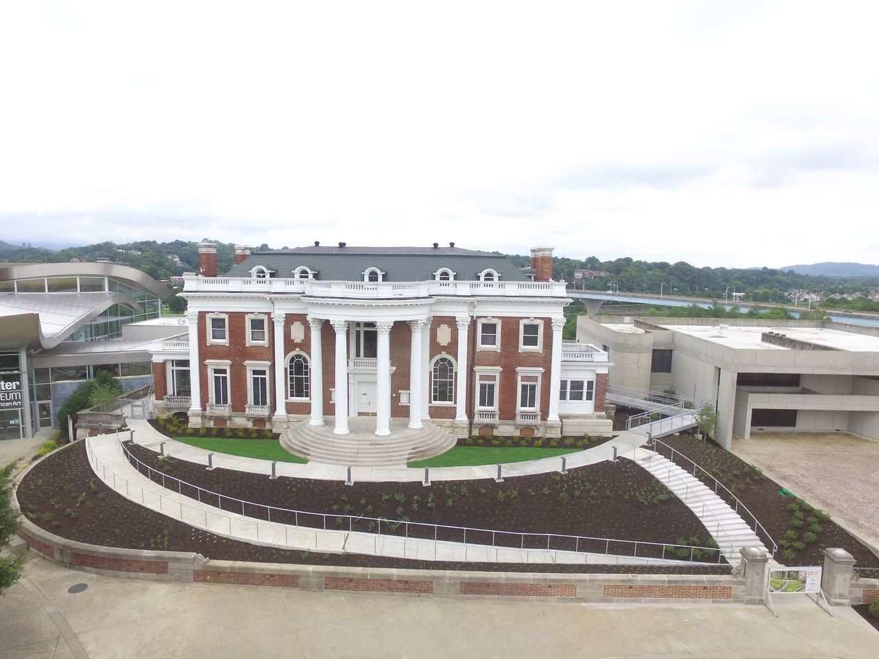 An aerial view of a large brick building with columns and a walkway leading to it.