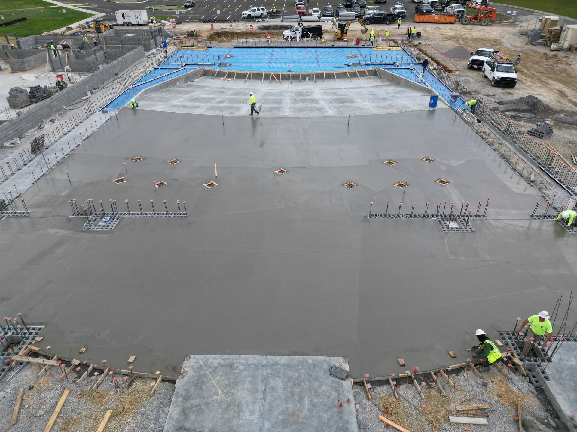 A group of construction workers are working on a large concrete surface.