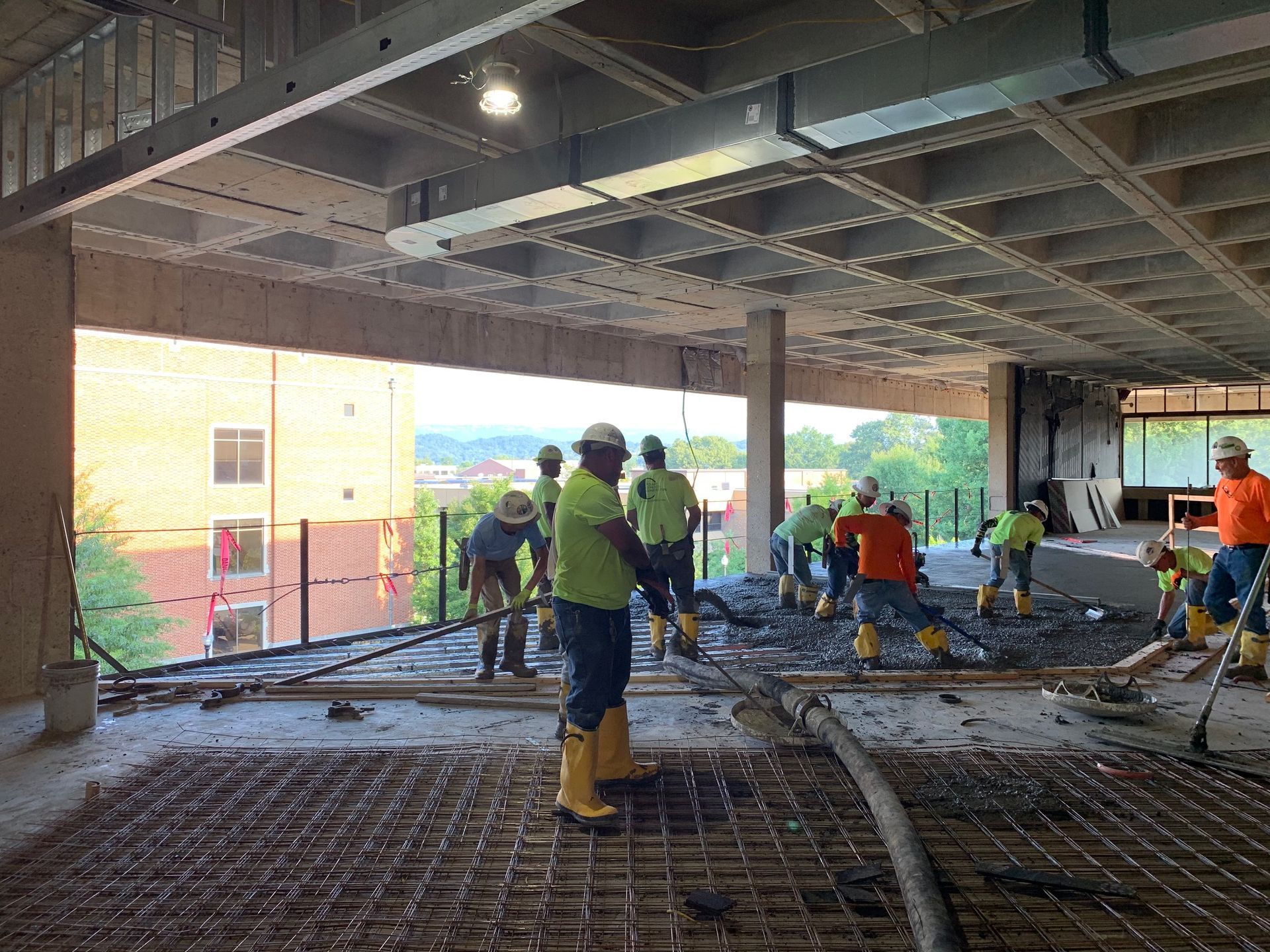A group of construction workers are working on a concrete floor.