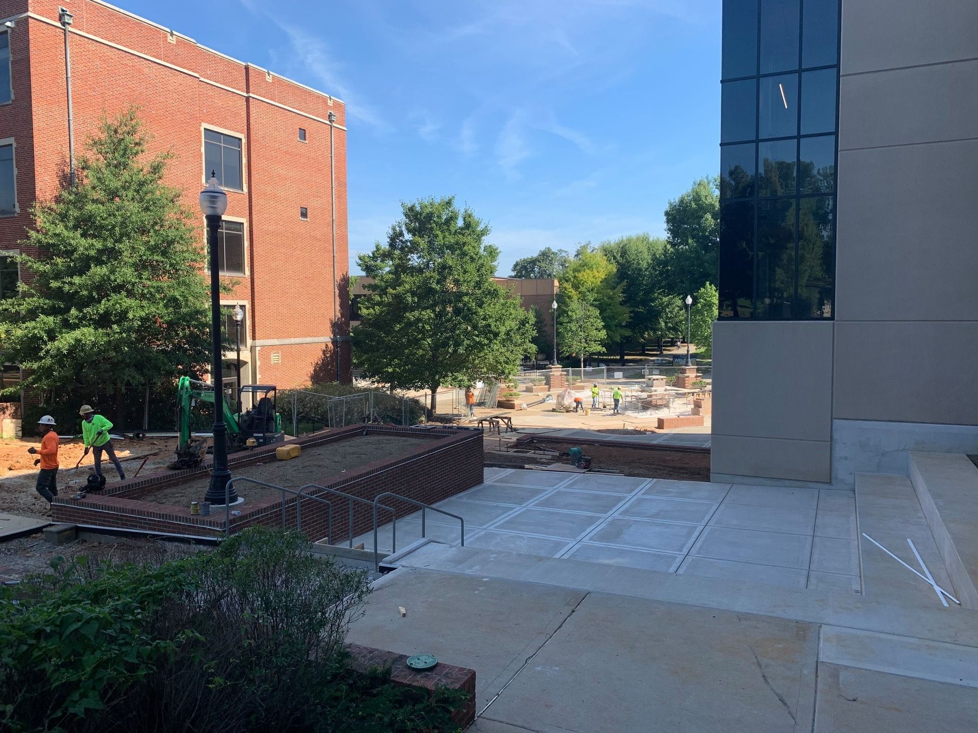 A group of construction workers are working on a sidewalk in front of a building.
